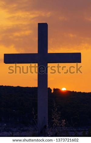 Silhouette of christian cross and sun setting behind the hill. Easter, Christmas, resurrection and religion concepts.
