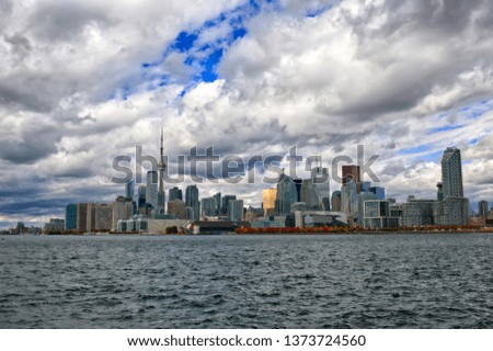 Big City beside lake, skyline, dynamic break in fluffy clouds, blue sky, dynamic water.