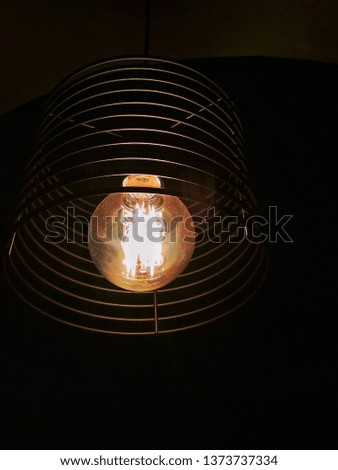 incandescent bulb in a modern lampshade in sharpness in a dark room