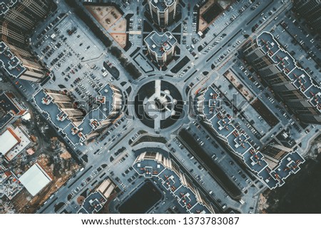 Top down aerial view of round road intersection with cars and new modern buildings, drone shot, toned
