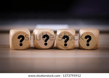 Four wooden blocks with black question marks.
