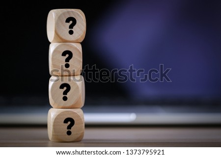 Four wooden blocks with black question marks.