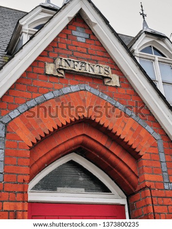 Very old red brick facade of a building with signage indicating an Infant entrance to a public building in London England.                               