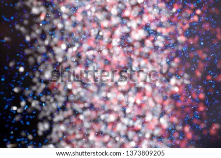 Mix of falling red, white, and blue sprinkles against a black background