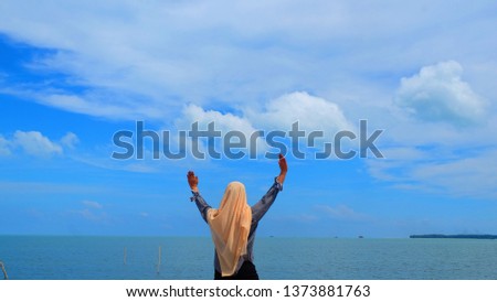 Hiker woman standing with hands up achieving the top. muslim Girl welcomes a beautiful. Conceptual design. Successful woman hiker open arms on sea sky. Girl in long white dress in the bluesky thailand