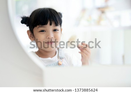 Asian cute smiling little girl with makeup brush. 