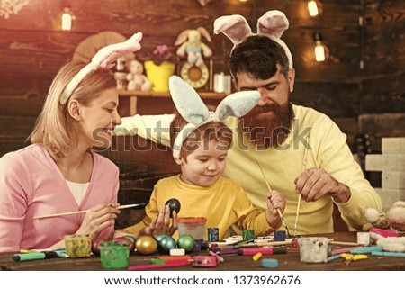 Easter egg ideas for happy family. Mother, father and son painting Easter eggs witht easter bunny costume and fake bunny ears.