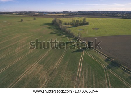 drone image. aerial view of rural area with fields and forests and water reflections in river in cloudy spring day. latvia - vintage old film look