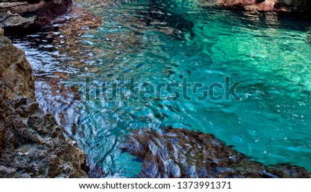 Turquoise water in Blue Grotto, Malta, close up. Maltese nature, Maltese coastline with emerald sea water and rocks, clear sea in Malta, social issue environment photo, clear sea and stones