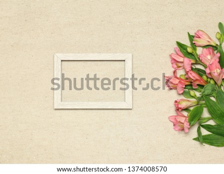 Flat lay frame with pink flowers on beige granite background
