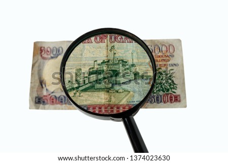Five thousand Ugandan shillings bill and magnifying glass isolated on white background, reverse side