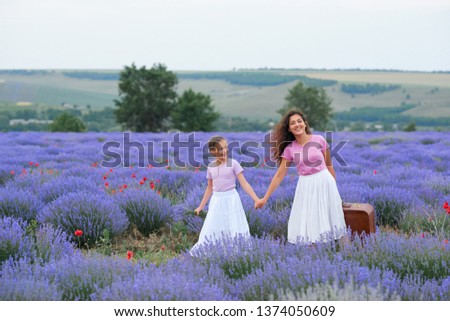 young woman and girl are walking through the lavender flower field, beautiful summer landscape