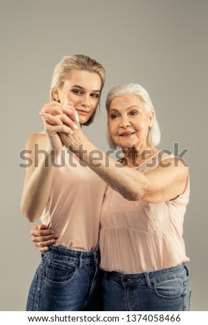 Emotional expression. Joyful happy mother and daughter smiling while standing together