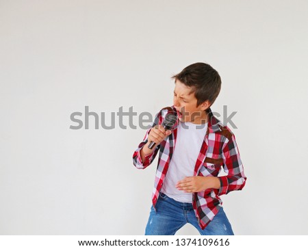 Little boy singing with microphone on grey background. Very emotional - Image