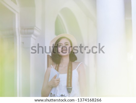 The image of an Asian woman smiling brightly while she was at her house. A beautiful Asian girl holds a notebook and looks outside while she is in the house.