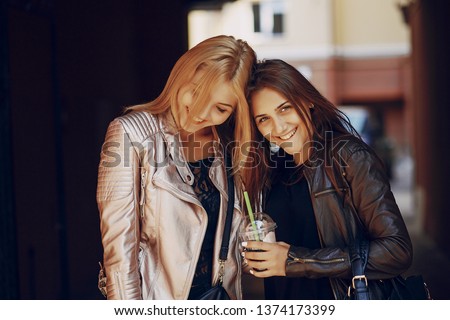 Two beautiful stylish girls walking and drink cocktails
