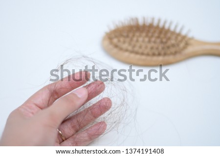 Hair loss in woman hands and comb.