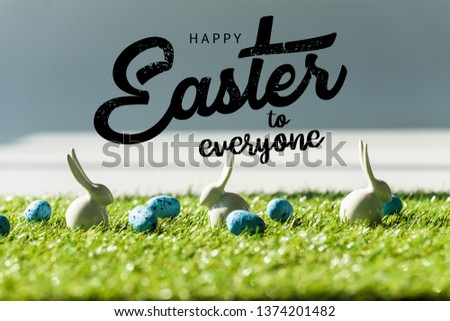 decorative rabbits on green grass near blue quail eggs with happy Easter to everyone illustration