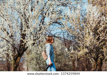 Girl photographer enjoying spring day in nature with a blooming cherry tree.
