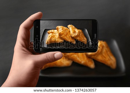 Hands of a man takes photos of food on the table with the phone. Fresh buns with vegetable filling. Wheat bread filling on a dark background. Photos of the smartphone for the post in social networks.