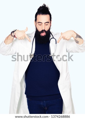 Doctor with long hair wearing medical coat and stethoscope Pointing down with fingers showing advertisement, surprised face and open mouth