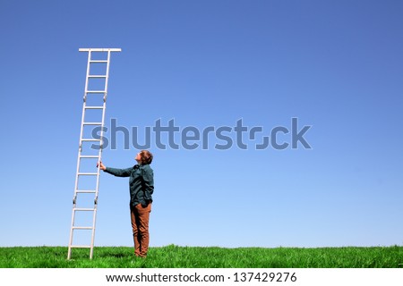 Young teenage boy holds a ladder on green meadow and blue sky