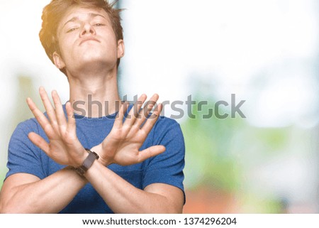 Young handsome man wearing blue t-shirt over isolated background Rejection expression crossing arms and palms doing negative sign, angry face