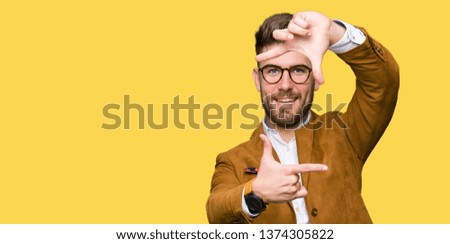 Young handsome business man wearing glasses smiling making frame with hands and fingers with happy face. Creativity and photography concept.