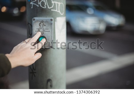 Young woman pushing button to cross the road