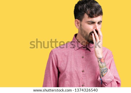 Young handsome man wearing pink shirt over isolated background bored yawning tired covering mouth with hand. Restless and sleepiness.