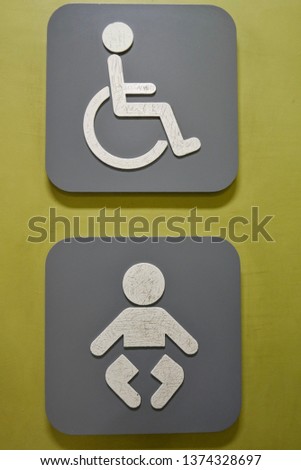 Symbol of disabled people and children in front of the bathroom