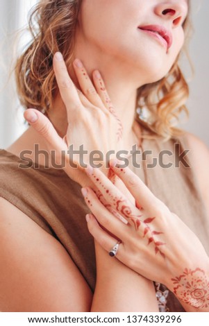 Crop portrait of beautiful young woman in linen dress with mehendi on hands, eco natural beauty