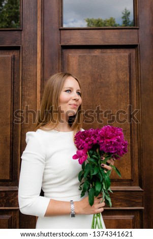 Young girl with a bouquet of bright peonies on a walk around the city