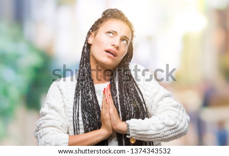 Young braided hair african american girl wearing sweater over isolated background begging and praying with hands together with hope expression on face very emotional and worried