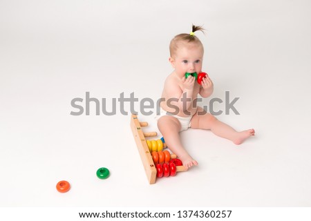 cute baby with developmental toy on a white background, bright picture of crawling curious baby over white backgroubd, 