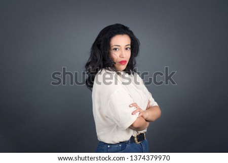 Image of cheerful pretty young caucasian businesswoman standing indoors with arms crossed. Looking and smiling at the camera. Confident girl.