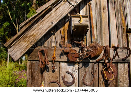 Rusty tools and farm implements against an old wooden barn wall.