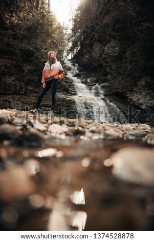 Young woman near fresh waterfall. Ecotourism concept