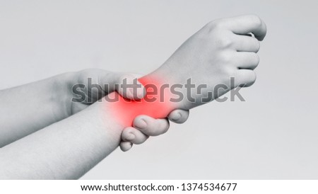 Office syndrome. Young woman massaging her painful wrist, monochrome photo with red sore zone