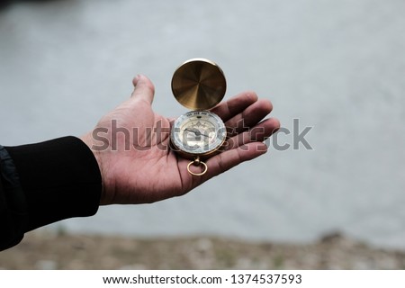 Man hands holding compass to find the direction in travel