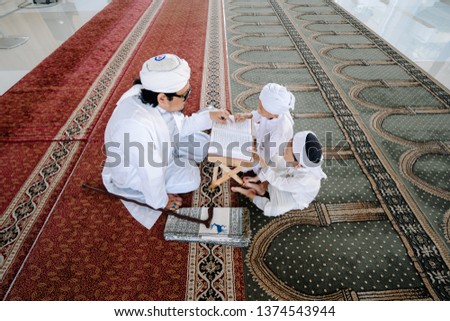 Concept of young asian Malay muslims learning reciting the holy Quran accompanied by their teacher