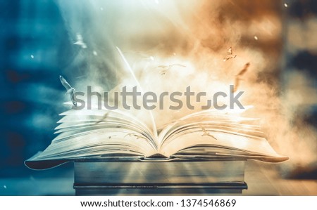 Imagine a picture book of an ancient book opened on a wooden table with a sparkling golden background. With magical power. magic. lightning around a glowing glowing book In the room of darkness Royalty-Free Stock Photo #1374546869