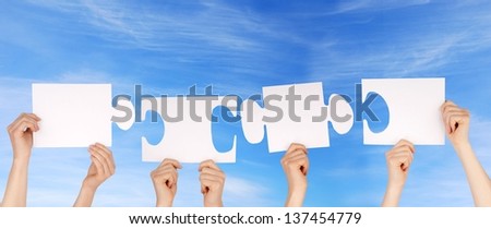 hands holding four pieces of a puzzle with copy space, gray background