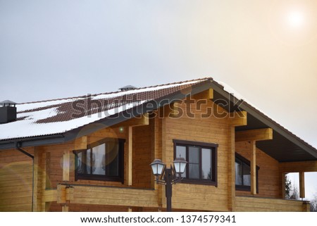 Part of the facade of a wooden house in modern style and sun rays. Natural photo.