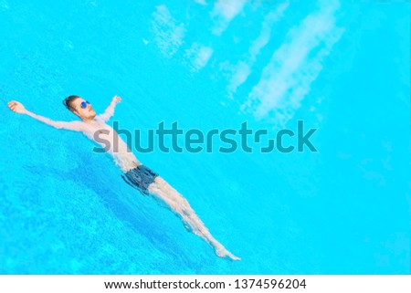 Man swimming in the pool. Top view of a man swimming in a swimming pool on warm and sunny summer day. Relax conception. Toned.