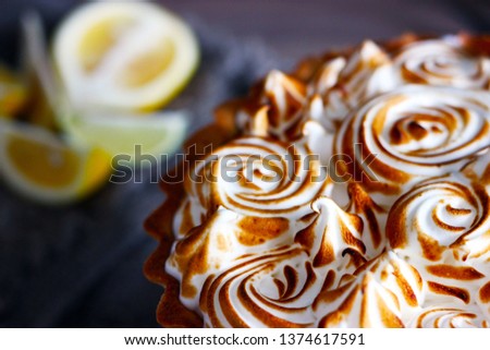 
Lemon tart close-up with meringue and lemon slices in the background in discreet colors