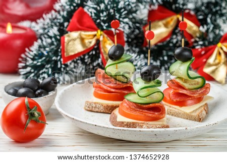 Delicatessen appetizer of bread, cheese, salami sausage, fresh tomatoes and cucumbers, black olives. Canape. Antipasti.  New year, Christmas, Thanksgiving. Selective focus