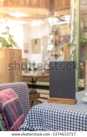Blank chalkboard standing on table over blur cafe with bokeh background, space for text