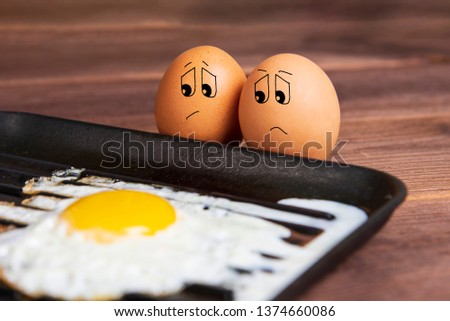 Eggs with a sad face near a fried egg. Humorous picture