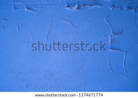 Fragment of a wall with scratches and cracks. Concrete wall with cracked blue paint.